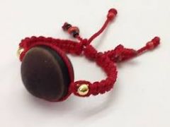 red yarn bracelet attached to a large seed, worn by infants to prevent effect of mal ojo