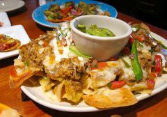 Seasoned (*Green chile*) shredded pork, 
-on our (*our house made*) tortilla chips, 
layered with
-melted  Jack cheese, 
-borracho beans and  
-topped with salsa Fresca, Chipotle sour cream, fresh jalapeños,
-served with hand-hacked guacamo...