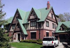 Variation of english tudor style is asymmetrical, has a very steep cross-gabled roof, a prominent chimney, and half-timbered exteriors.