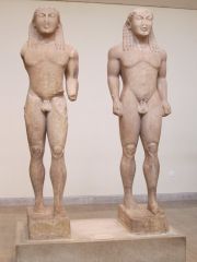 An archaic Greek statue of a standing nude male.