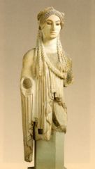An archaic Greek statue of a standing, draped female.