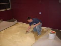 The installation of the carpet backing by adhering it directly to the flooring with an adhesive.