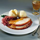 roast pork often served with Semmelkoedel (Bavarian bread dumplings), applesauce and red cabbage